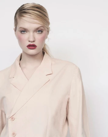 Portrait of a woman with red lipstick wearing a pale pink blazer against a plain white background