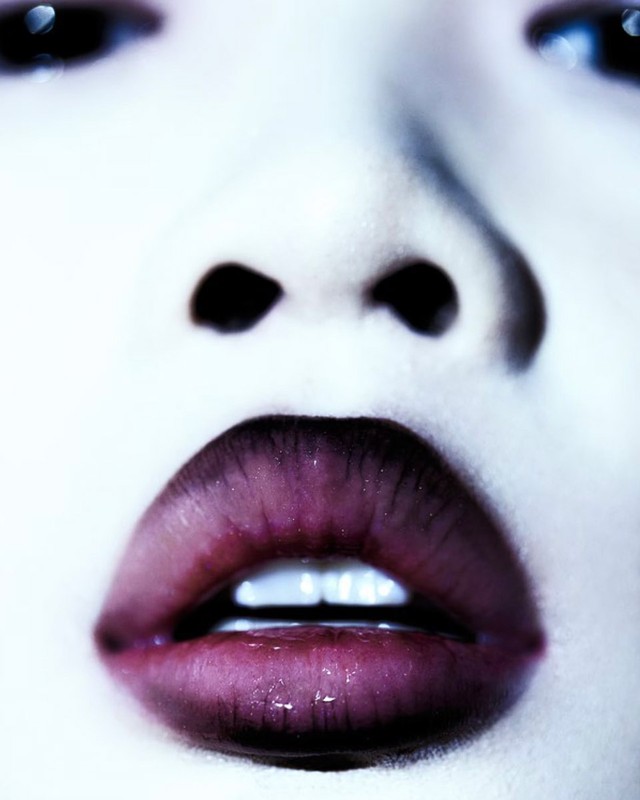 Close-up portrait of a woman with dark lined lips and white teeth by make-up artist David Razzano