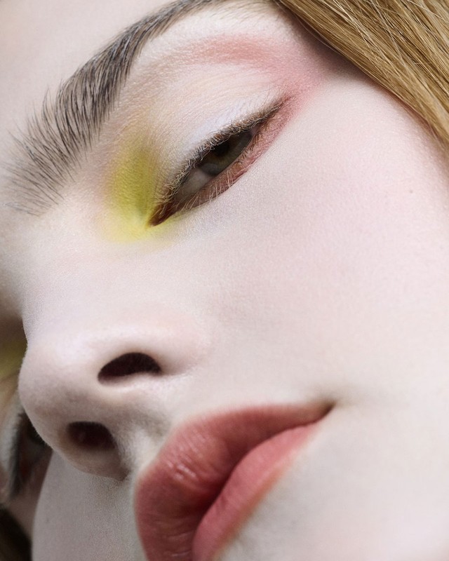 Close-up portrait of a model with artistic makeup featuring yellow eyeshadow, pink accents, and muted rose lipstick by David Razzano.