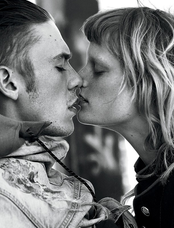 Black and white portrait of a couple kissing with a shallow depth of field. The male figure wears a jean jacket.
