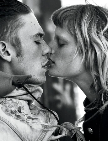 Black and white portrait of a couple kissing with a shallow depth of field. The male figure wears a jean jacket.