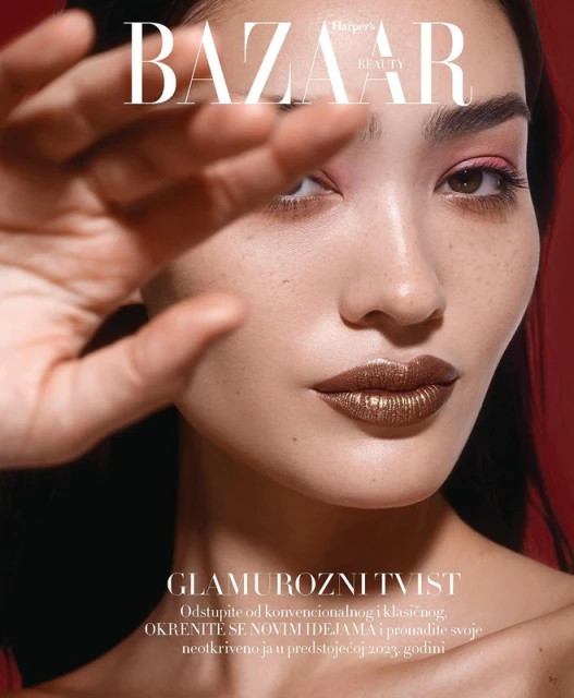 Magazine cover featuring a close-up portrait of a woman with dramatic makeup, including glossy lipstick and pink eyeshadow, against a red backdrop.