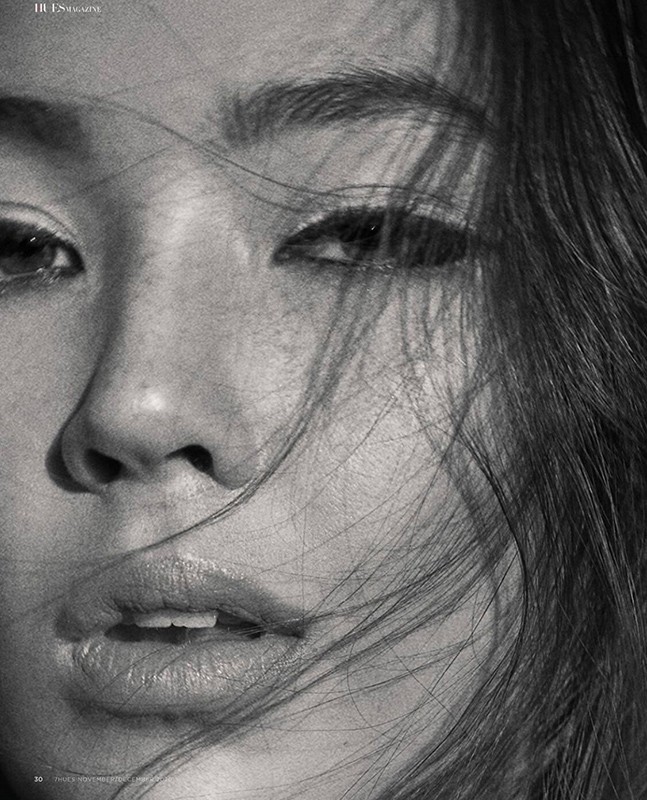 Close-up black and white portrait of a young Asian adult female with dark hair framing her face, soft light and selective focus.