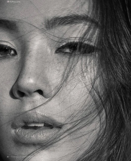 Close-up black and white portrait of a young Asian adult female with dark hair framing her face, soft light and selective focus.