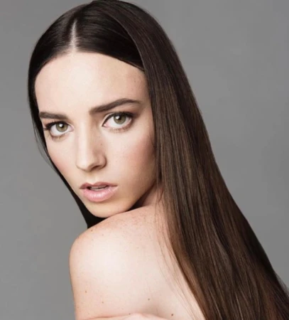 Close-up portrait of a woman with long straight dark brown hair and soft makeup against a neutral grey background.