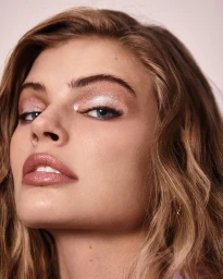 Close-up portrait of a woman with shimmery eyeshadow and wavy blonde hair by hair stylist Destiny Venice.