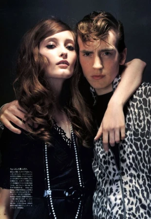 Stylish portrait of a fashionable couple, featuring a young adult woman with long wavy hair and a young adult man in a leopard-print jacket.