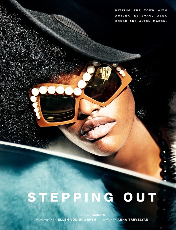 Portrait of a dark-skinned woman with curly hair, wearing pearl-studded sunglasses and a black hat, with a fur shawl. Fashion shot.