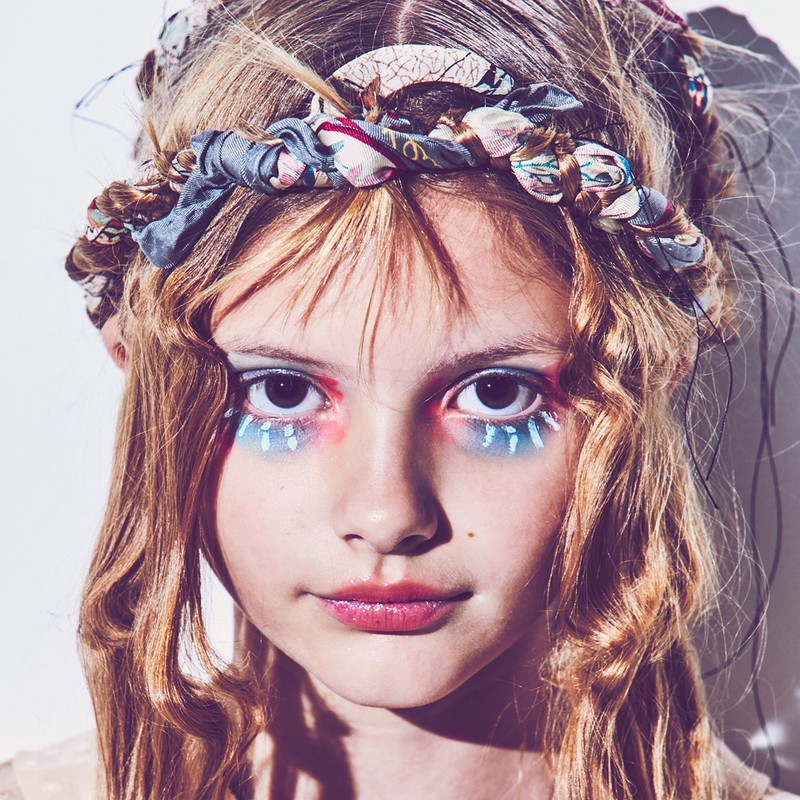 Close up portrait of a young model with colorful eye makeup and a patterned fabric headband in Los Angeles.