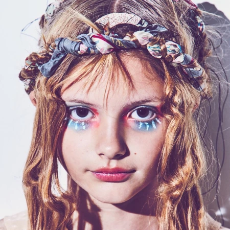 Close up portrait of a young model with colorful eye makeup and a patterned fabric headband in Los Angeles.
