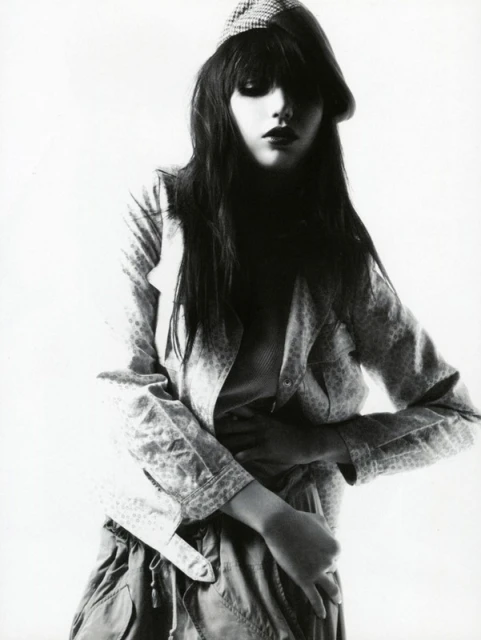 Young woman in jacket and cap poses in a studio fashion shot. Dark hair and eyes. Monochrome image. Studio lighting. Youth fashion concept.