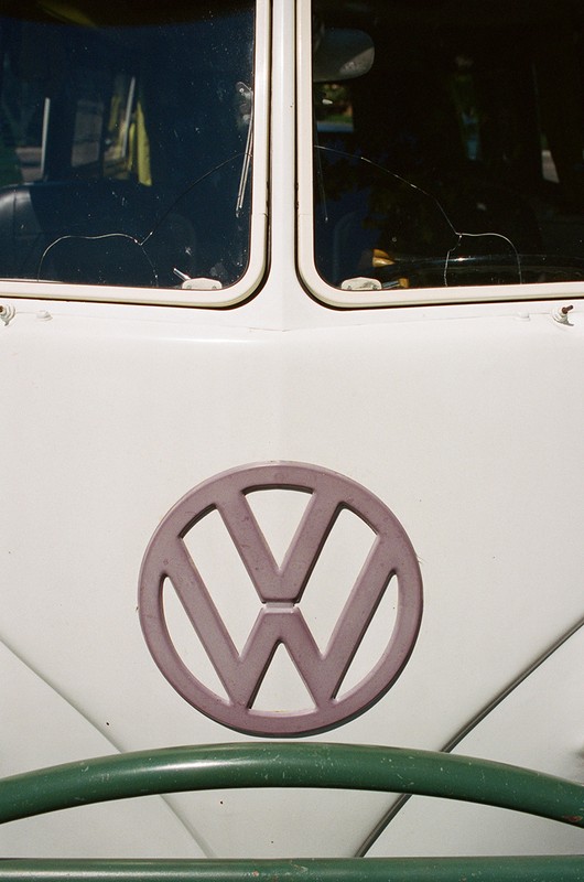 Close-up of a vintage Volkswagen bus with a white exterior, green bumper, and prominent VW logo, capturing a retro automotive aesthetic.