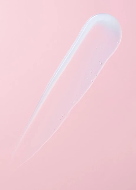 Clear gel serum skincare swatch on a pink background. Minimalist beauty and cosmetic product photography for skin treatment ad campaign.