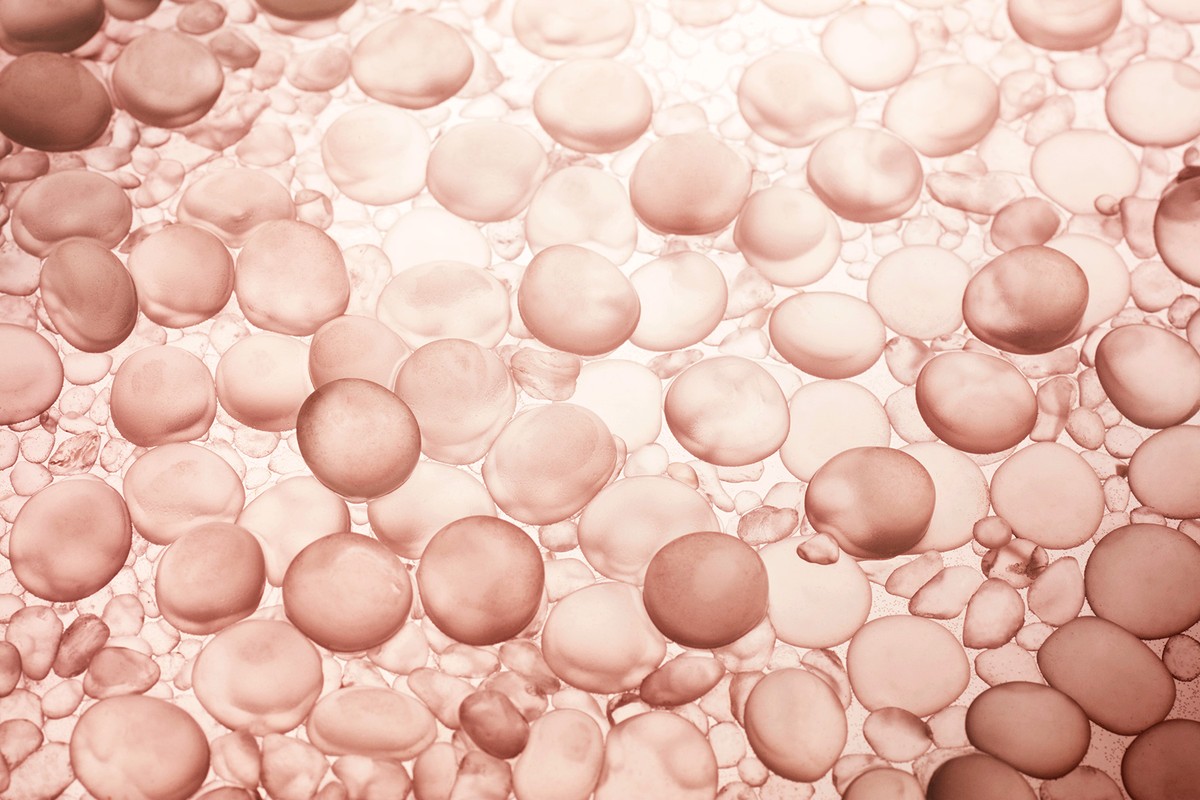 Close-up of small, round gel beads in shades of pink, peach, and white, creating a textured surface with a soft, diffused light.