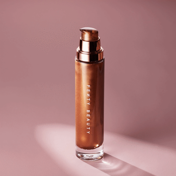 Product shot of Fenty Beauty body luminizer in a glass bottle with pump against a mauve backdrop, highlighting the bronze shimmer.