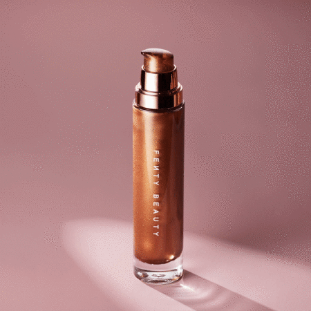 Product shot of Fenty Beauty body luminizer in a glass bottle with pump against a mauve backdrop, highlighting the bronze shimmer.