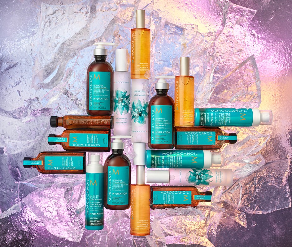 Still life of Moroccanoil hair product bottles against an iridescent background with turquoise, brown, yellow, and white bottles and containers.