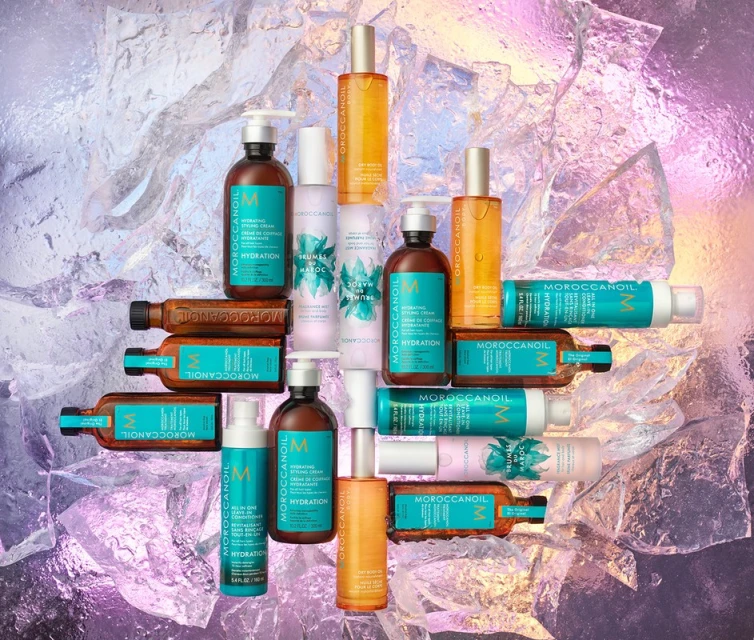 Still life of Moroccanoil hair product bottles against an iridescent background with turquoise, brown, yellow, and white bottles and containers.