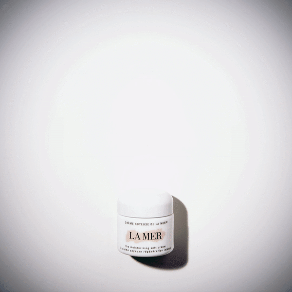 Close-up of a white jar of La Mer moisturizing cream on a white surface, captured with soft, diffused lighting and minimal composition.