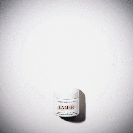 Close-up of a white jar of La Mer moisturizing cream on a white surface, captured with soft, diffused lighting and minimal composition.