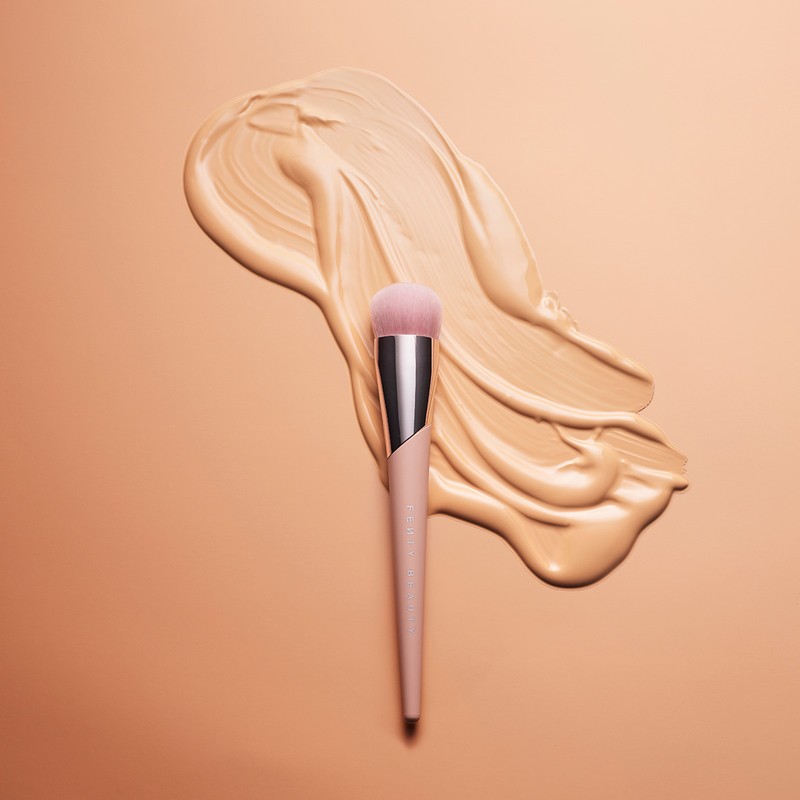 Close-up shot of a makeup brush laying on top of spilled foundation, creating a visually appealing beauty product still life.