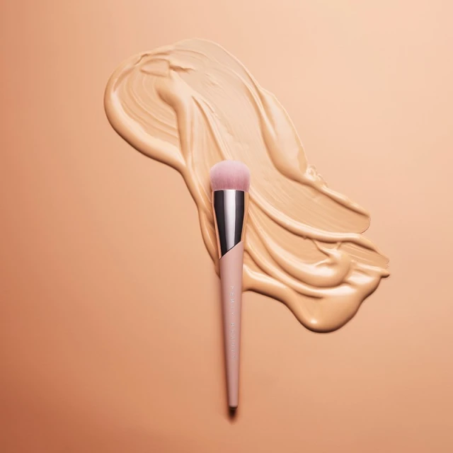 Close-up shot of a makeup brush laying on top of spilled foundation, creating a visually appealing beauty product still life.