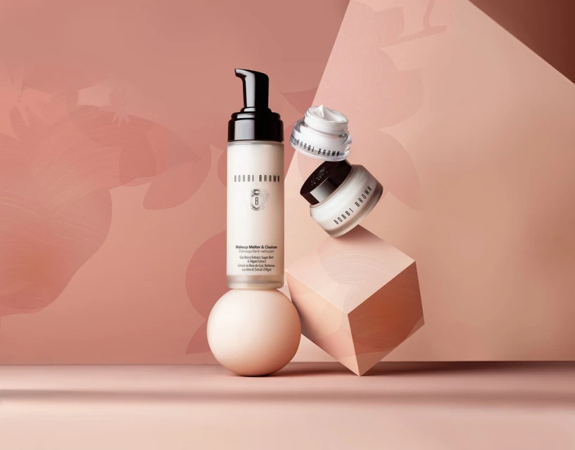 Bobbi Brown skincare products are displayed on a sphere and cube against a peach background in a studio product shot.