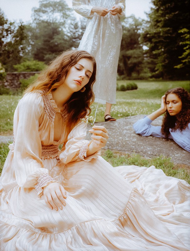 Three models wearing vintage-style dresses outdoors in a grassy park setting, styled by Doria Santlofer.