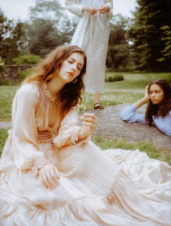 Three models wearing vintage-style dresses outdoors in a grassy park setting, styled by Doria Santlofer.