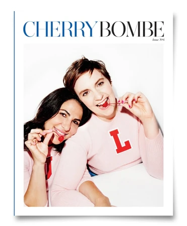 Magazine cover featuring two smiling women in pink sweaters, each holding a cherry, against a bright white background.