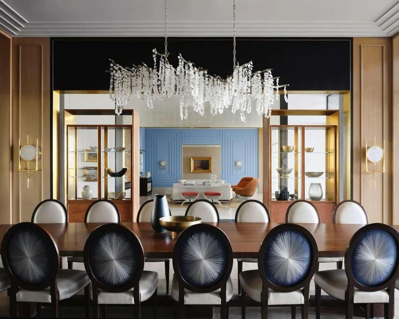 Contemporary dining room interior with a dark wood table, decorative chairs, and an ornate crystal chandelier hanging overhead.