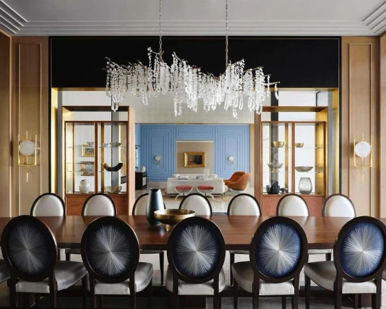 Contemporary dining room interior with a dark wood table, decorative chairs, and an ornate crystal chandelier hanging overhead.
