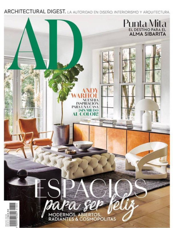 Architectural Digest magazine cover showcasing a modern interior with a tufted ottoman, colorful furniture, and a large potted plant.