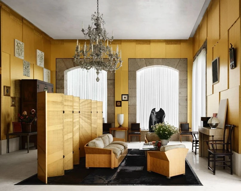 Ornate living room showcases wood screen, chandelier, patterned textiles, and stone-framed windows, creating an elegant and spacious interior.