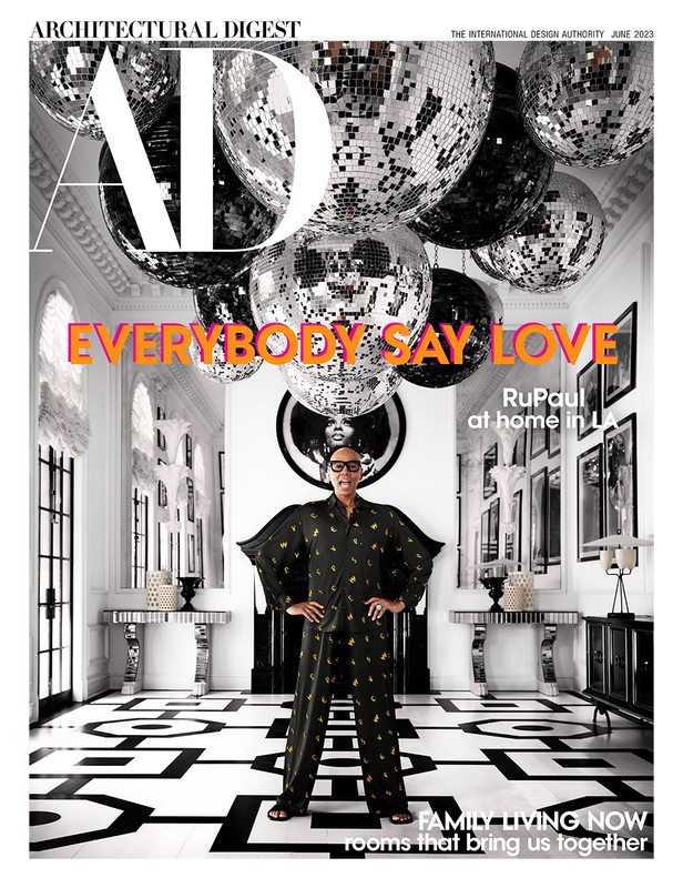 Architectural Digest magazine cover featuring RuPaul in a patterned pajama set, posing in a white interior with disco balls overhead.