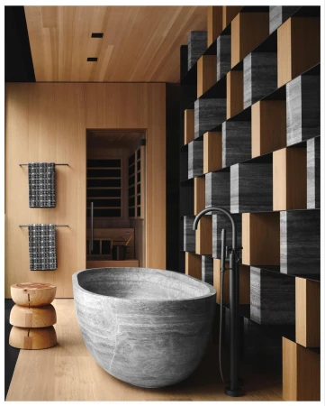 Stone bathtub is the focal point of a modern bathroom with wood paneled walls and floor, and a decorative partition.