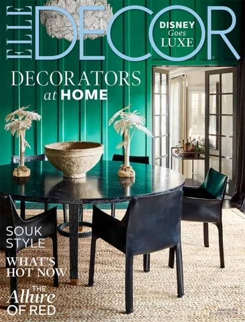Elle Decor magazine cover featuring a dining room with a round table, chairs, a textured bowl, and palm-shaped decor against a green wall.