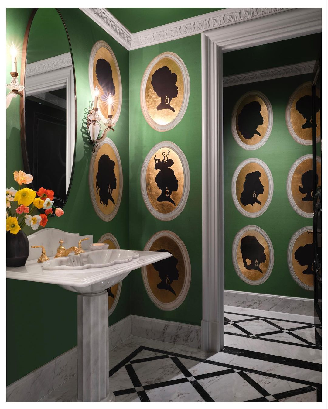 Interior bathroom features green walls adorned with framed silhouette portraits, a marble sink with gold fixtures, and a patterned floor.