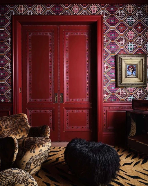 Intricate room interior featuring patterned wallpaper, ornate red double doors, an area rug with a tiger stripe pattern, and furniture.