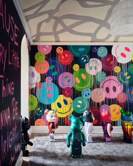 Colorful room with smiley-face art and designer toy figures. Black wall with text and a light-gray patterned ceiling.