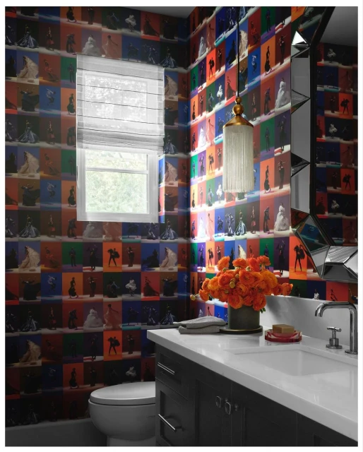 Powder room featuring bold wallpaper, a decorative mirror, sink and vanity, toilet, window, and orange flower arrangement.