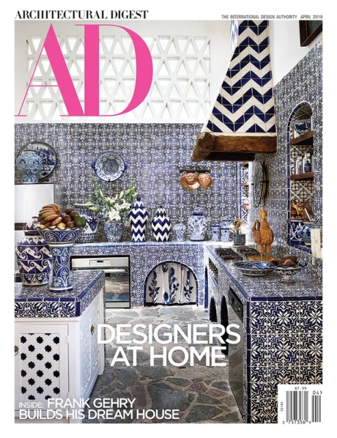 Architectural Digest magazine cover featuring a blue and white tiled kitchen with decorative pottery and fruit, promoting interior design.