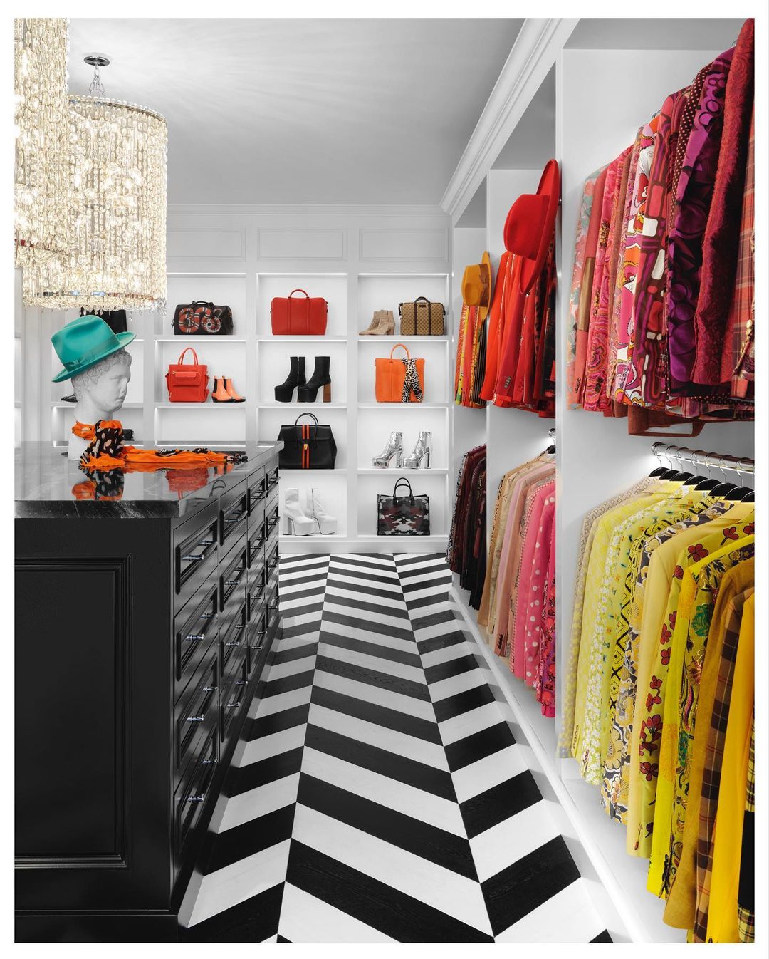 Elegant walk-in closet featuring organized clothes, handbags, shoes displayed on shelves, complemented by a black and white chevron floor.