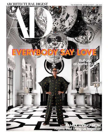 Architectural Digest cover featuring RuPaul in patterned pajamas, standing in a black and white patterned room with disco balls hanging from the ceiling.