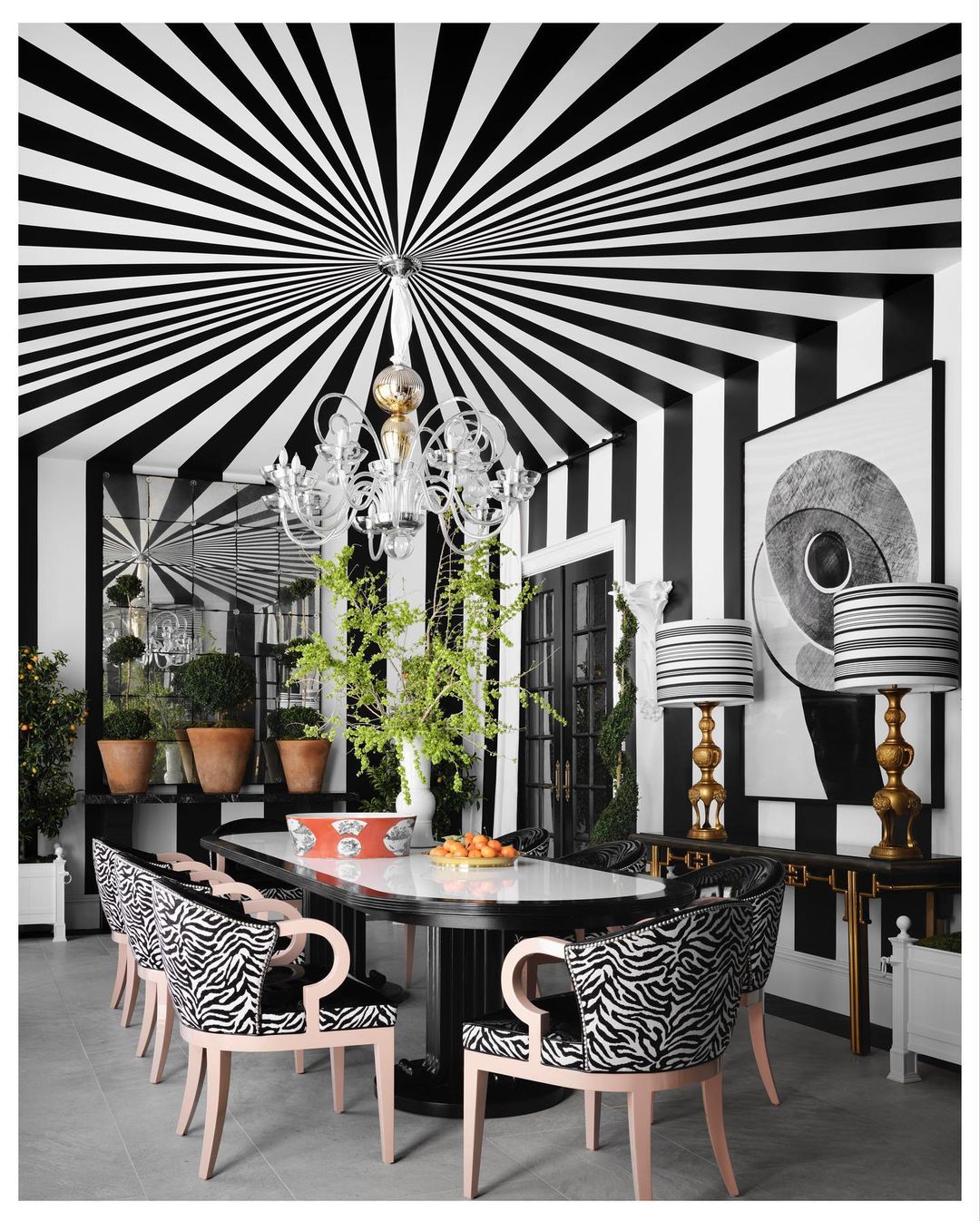 Luxurious dining room interior with black and white striped walls and ceiling, zebra print chairs, and a chandelier.