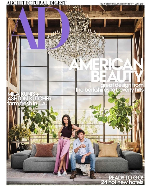 Architectural Digest cover featuring Mila Kunis and Ashton Kutcher on a gray couch, with a chandelier, large windows, and plants.