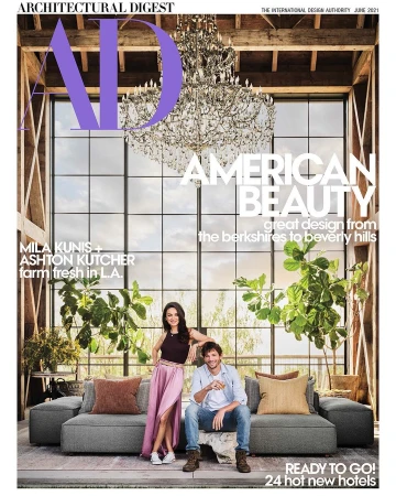 Architectural Digest cover featuring Mila Kunis and Ashton Kutcher on a gray couch, with a chandelier, large windows, and plants.