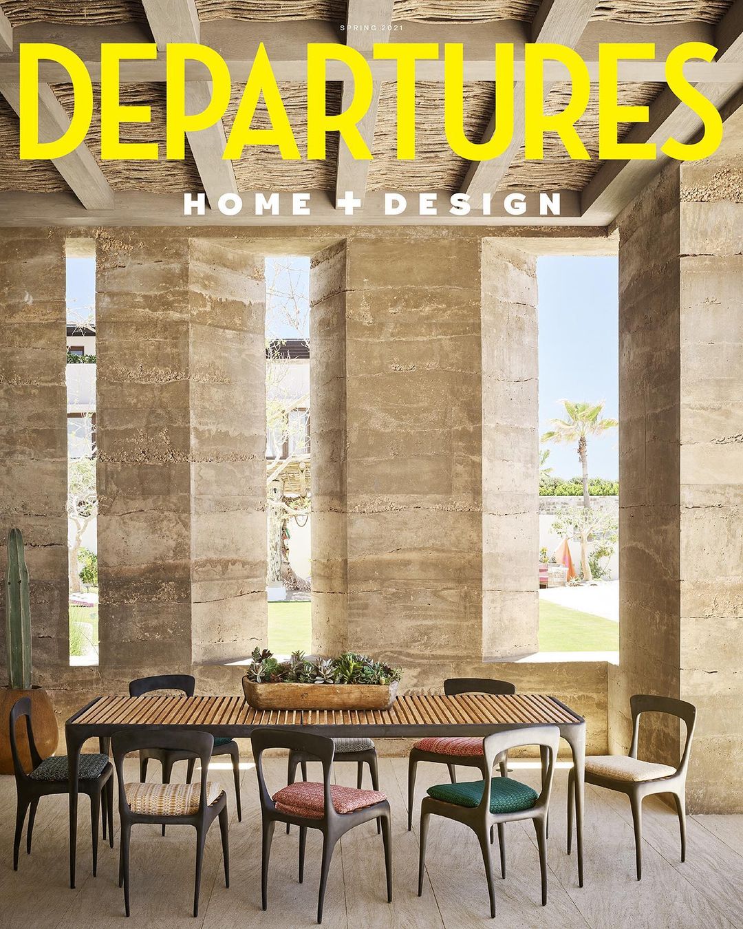 Departure's magazine cover showcases modern dining room with stone walls, long wooden table, and chairs under natural light.