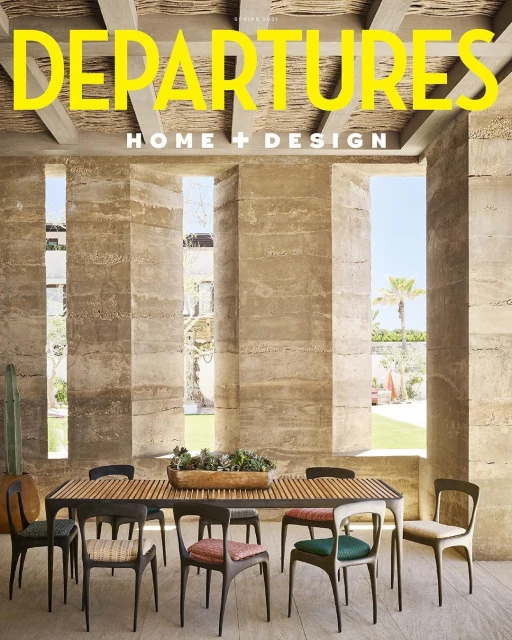 Departure's magazine cover showcases modern dining room with stone walls, long wooden table, and chairs under natural light.