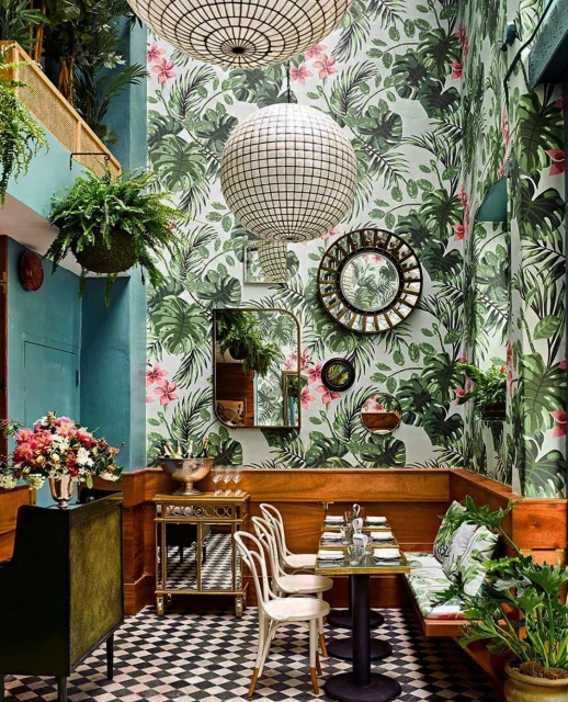 Indoor dining area with tropical leaf wallpaper, pendant lighting, wooden booths, and black-and-white checkered flooring creates a stylish ambiance.